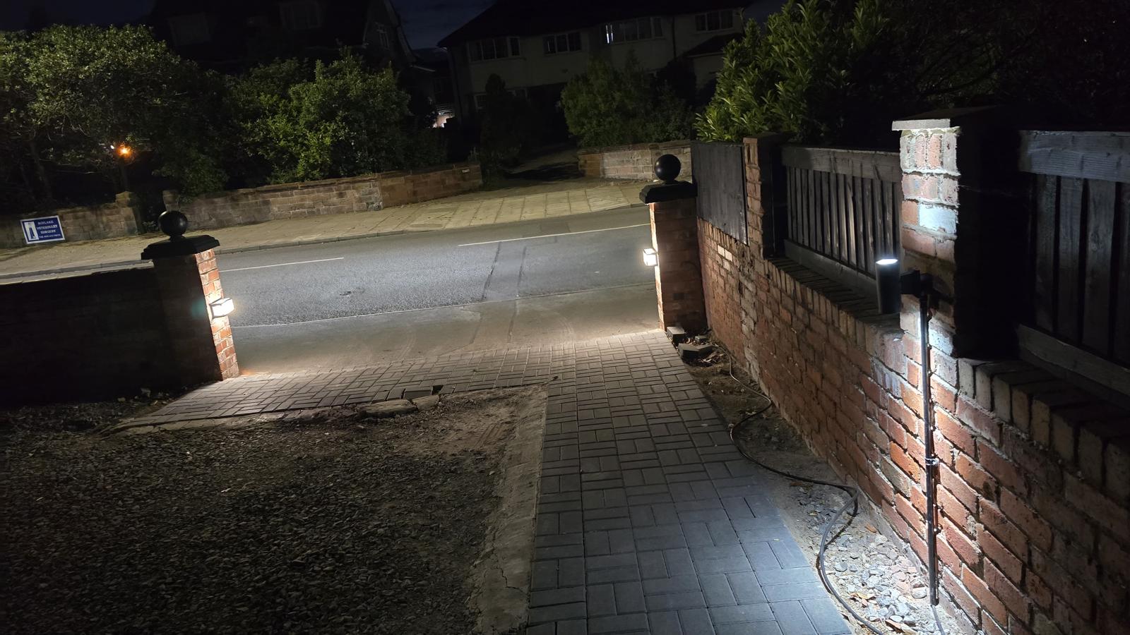 Driveway gate with professionally installed outdoor lighting at night — Wirral